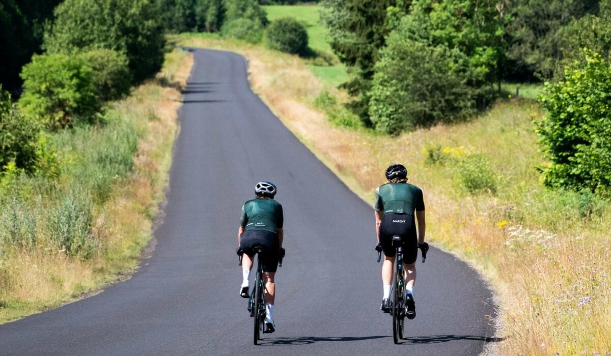 deux cyclistes en train de rouler sur une route en plein été