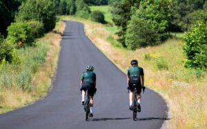 deux cyclistes en train de rouler sur une route en plein été